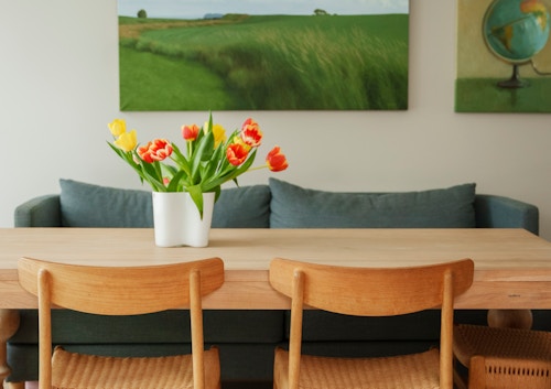 Et bilde av spisebordet i leiligheten på Vitigrend. På veggen henger det to malerier i grønnfarger.