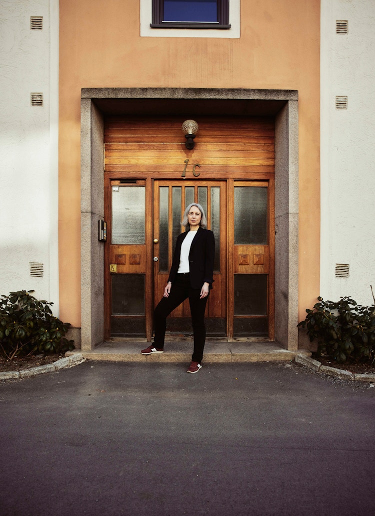 Foto av Anne Kristine Kronborg som står foran en brun inngangsdør i en OBOS-blokk