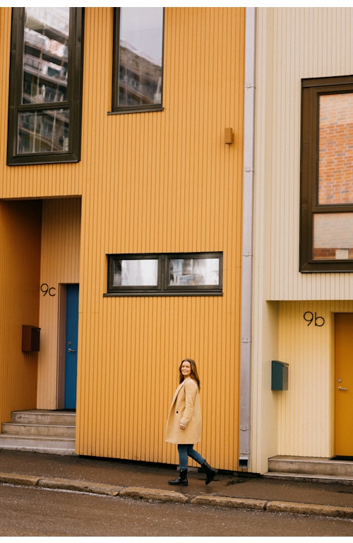 Portrett av Maria Tøsse gående foran fasader på Grünerløkka i Oslo.