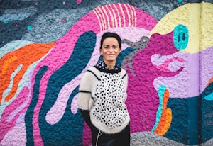 Mihaela står foran en fargerik vegg og smiler mot kameraet.