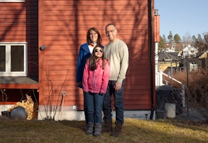 obos deleie familie på tre står foran et rødt hus