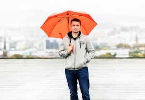 Styrelederen står på taket av Dynekilgata 15 borettslag med en oransje paraply