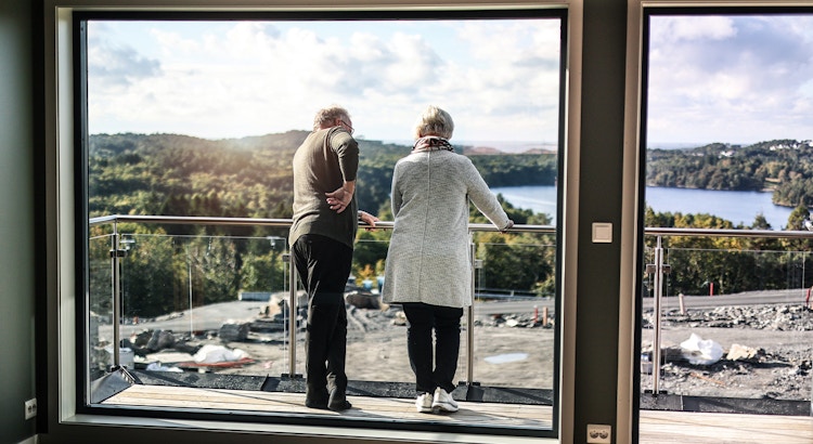 Mann og dame står på sin nye balkong med utsikt mot Drangsvannet.