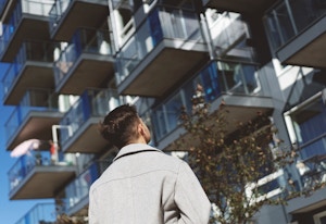 En mann står med ryggen og ser på en fasade.